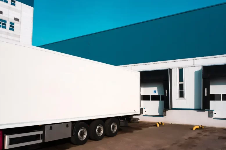 Unloading cargo truck at warehouse building.